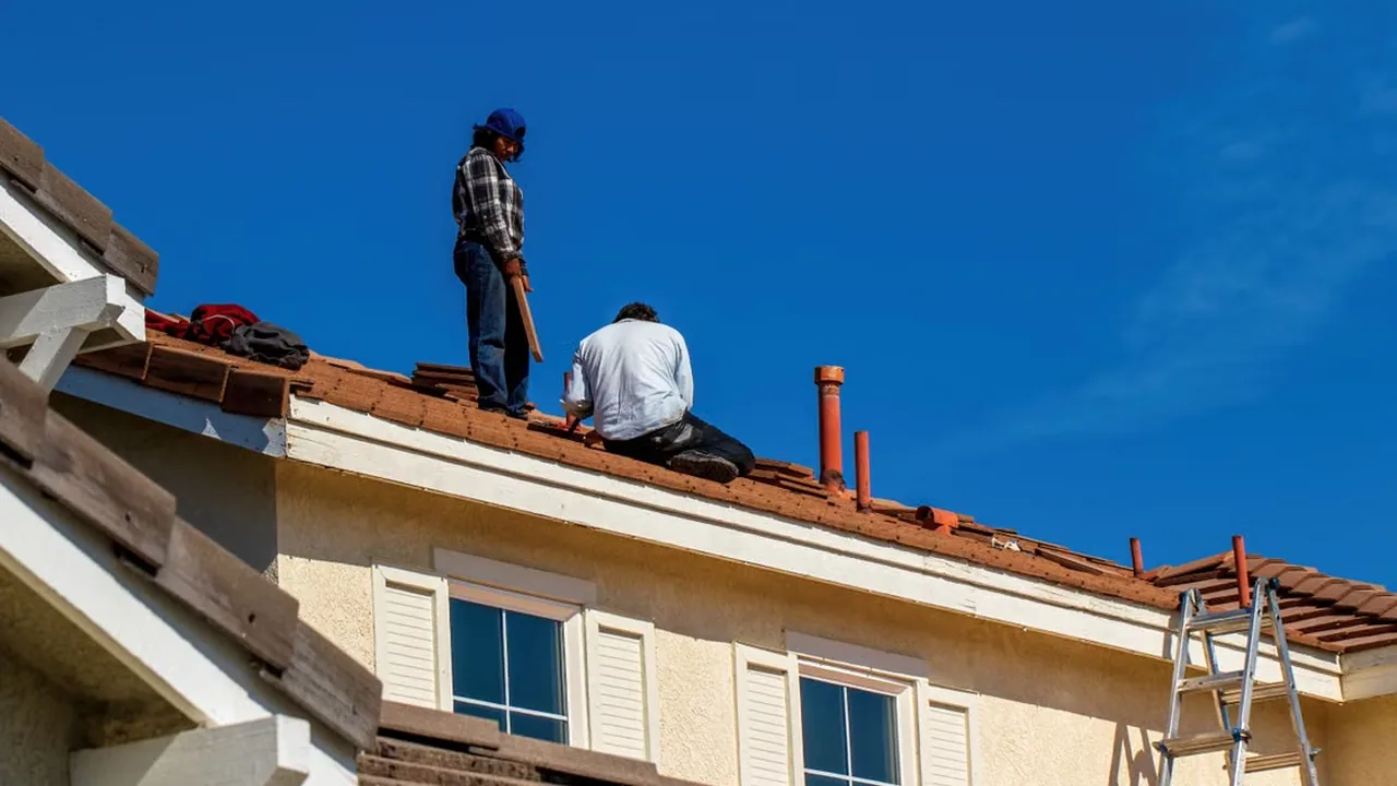 Low-angle shot of roofers fixing a roof against a blue sky